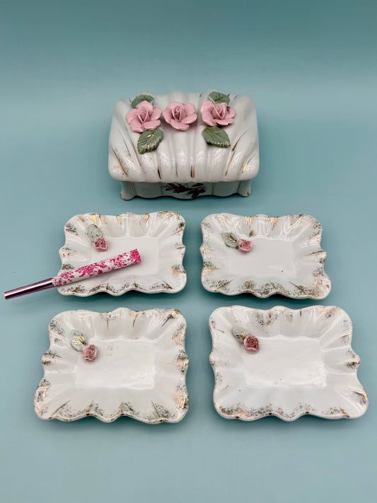 Porcelain stash box topped with dimensional pink roses, surrounded by four matching scalloped mini trays, teal background