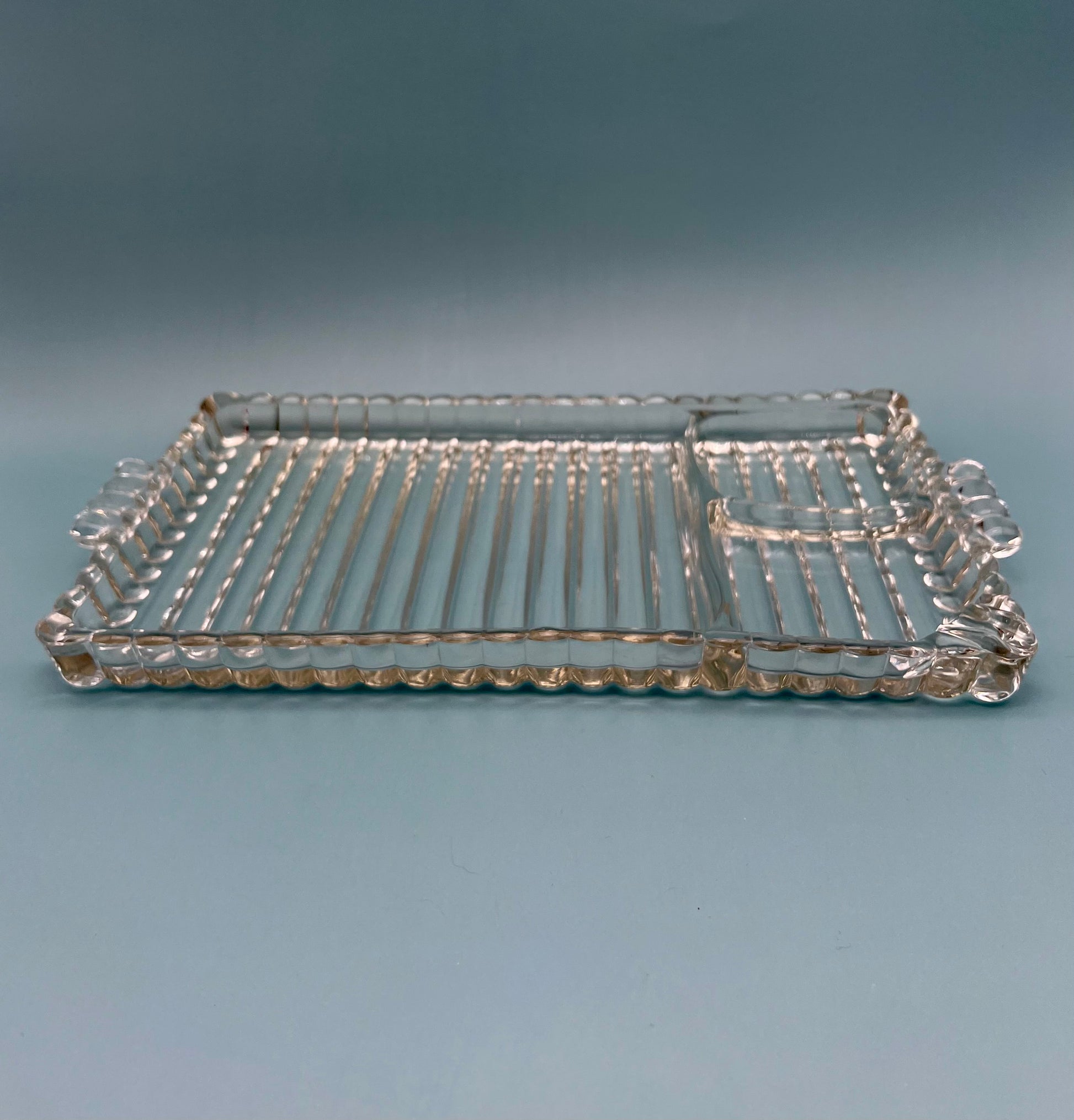 Close-up of the Hazel Set pressed glass tray showing its ribbed geometric pattern and scalloped rim, gray background.