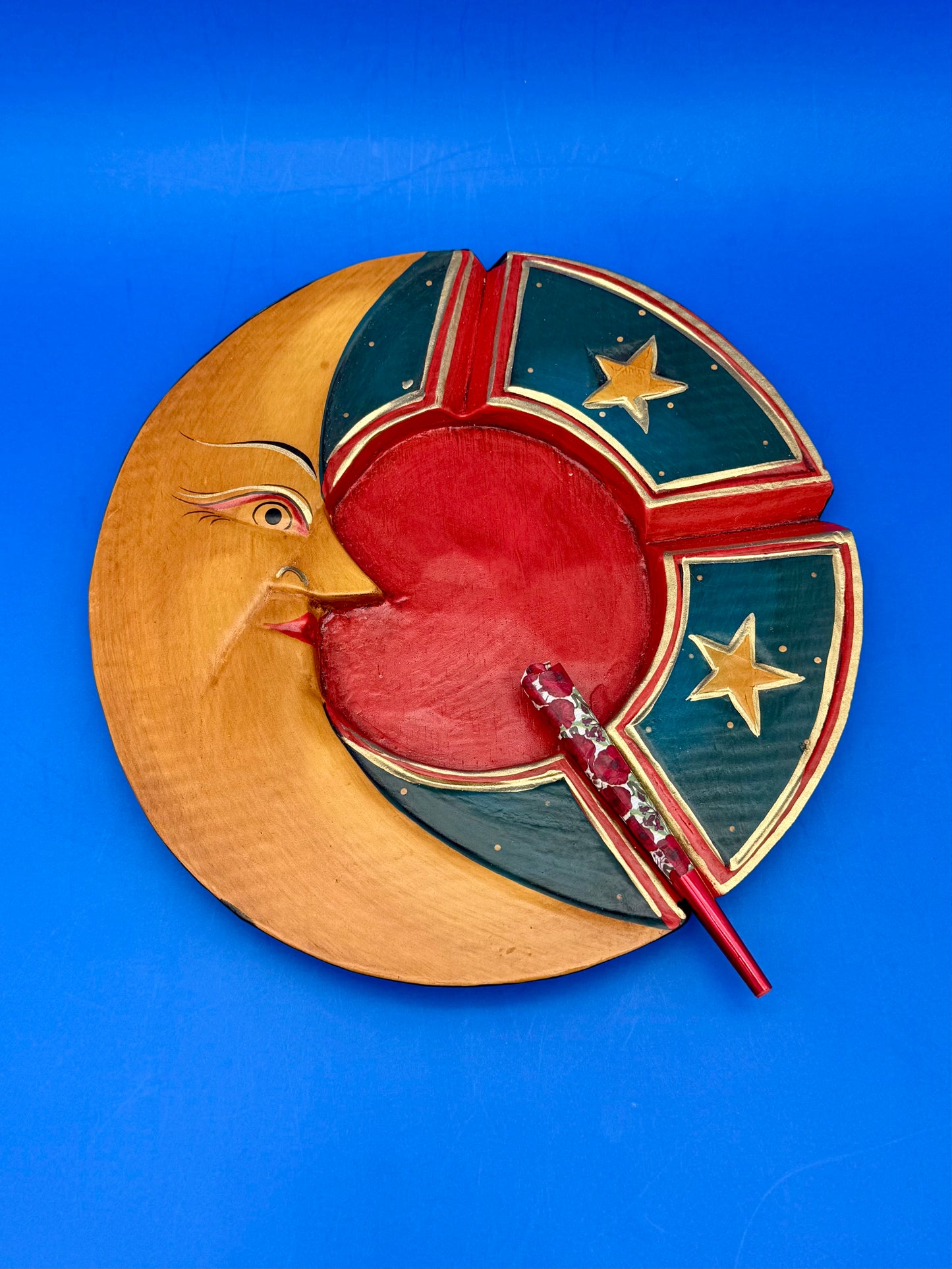 Hand-painted wooden ashtray with a golden crescent moon and red center, blue background