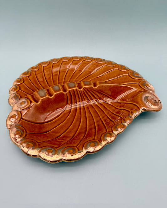 Large glossy amber brown paisley-shaped ashtray with radiating grooves and spiral edge detail, gray background