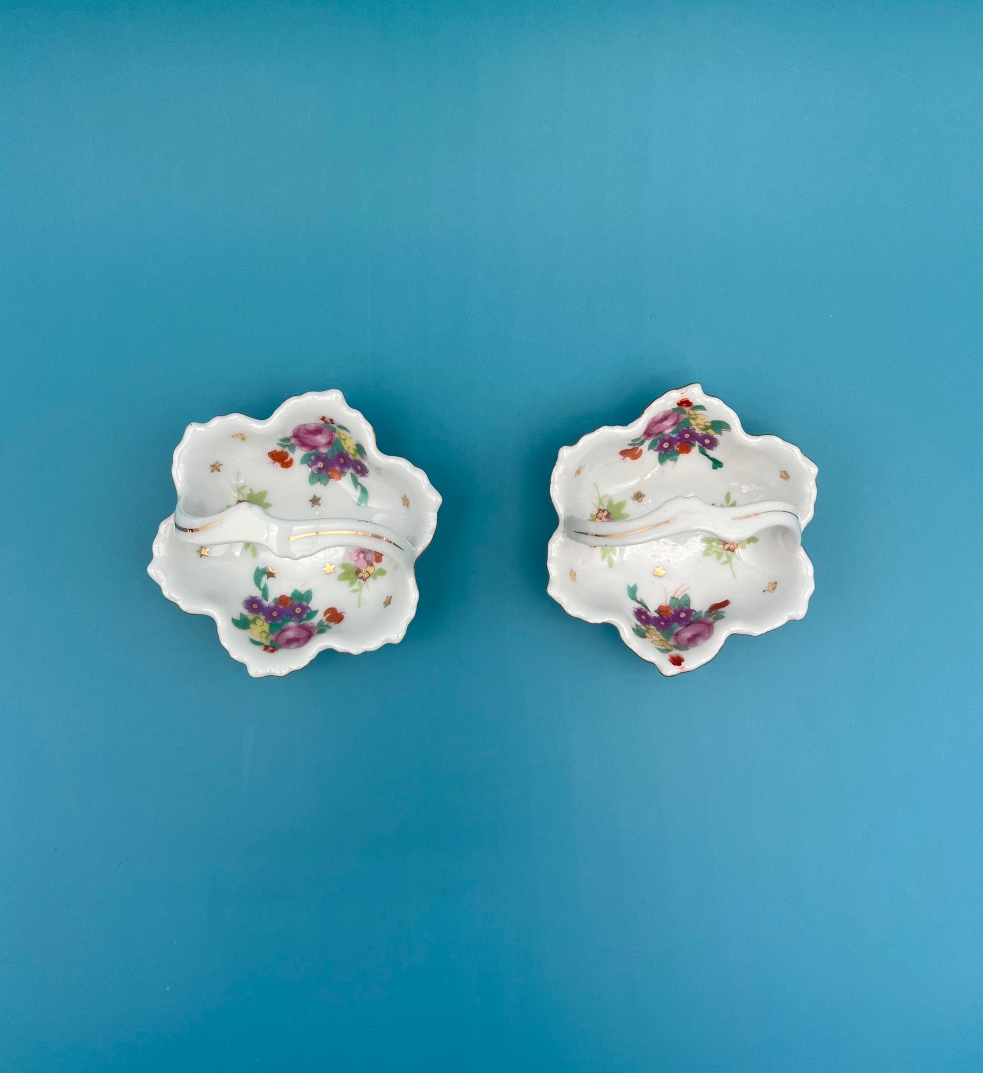 Top-down view of the Reagan Set porcelain ashtrays showing the floral pattern and gold star accents, teal background.