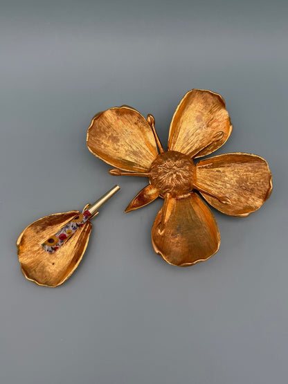 Gold marigold flower-shaped dish with five cupped petals, paired with a small teardrop-shaped dish holding a glass cigarette pick, gray-blue background.