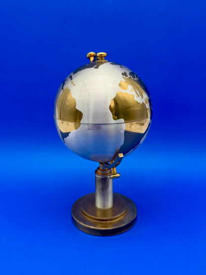 Close-up of the closed brass globe cigarette holder showing engraved continent detail