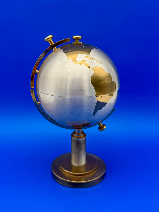 Brass globe cigarette holder closed on its pedestal stand, blue background