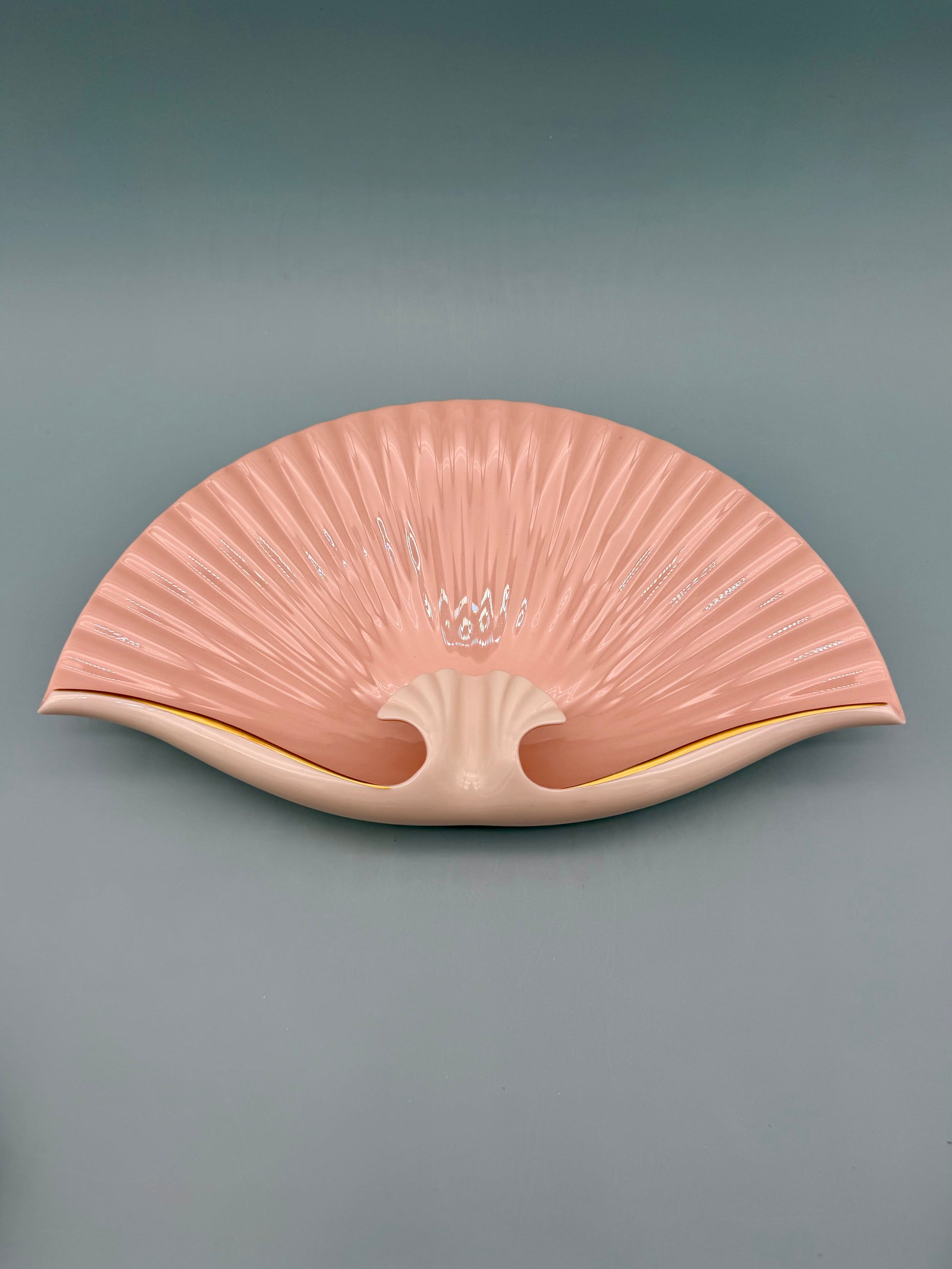Seashell-shaped porcelain ashtray with delicate pink floral detail at the center, gray background
