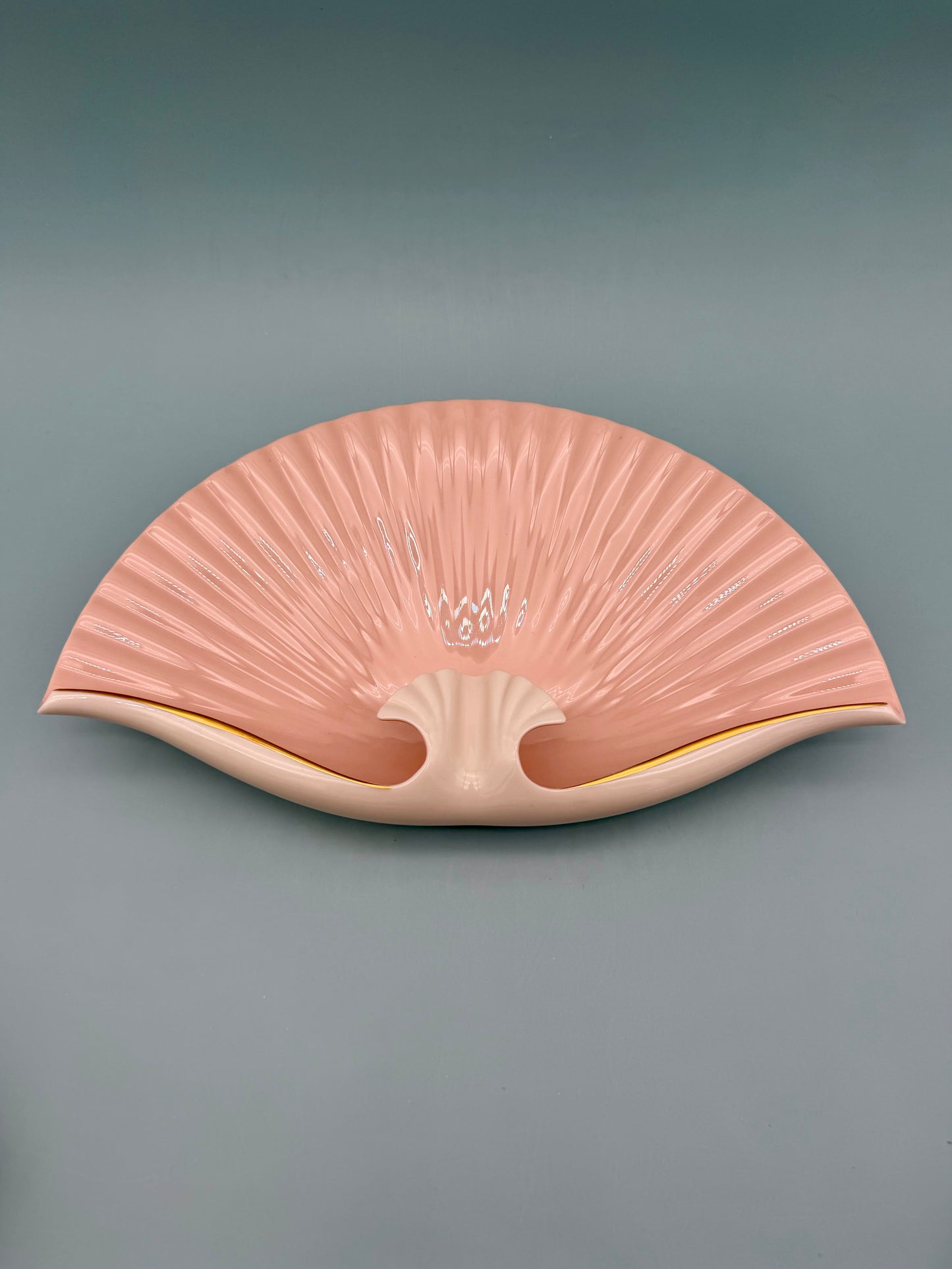 Seashell-shaped porcelain ashtray with delicate pink floral detail at the center, gray background