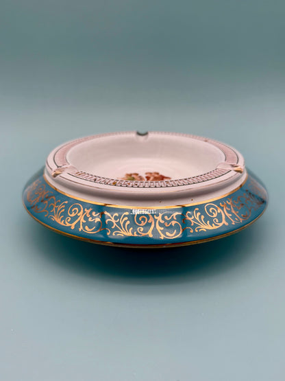 Turquoise and gold dancing figures ashtray shown from a side profile, gray background
