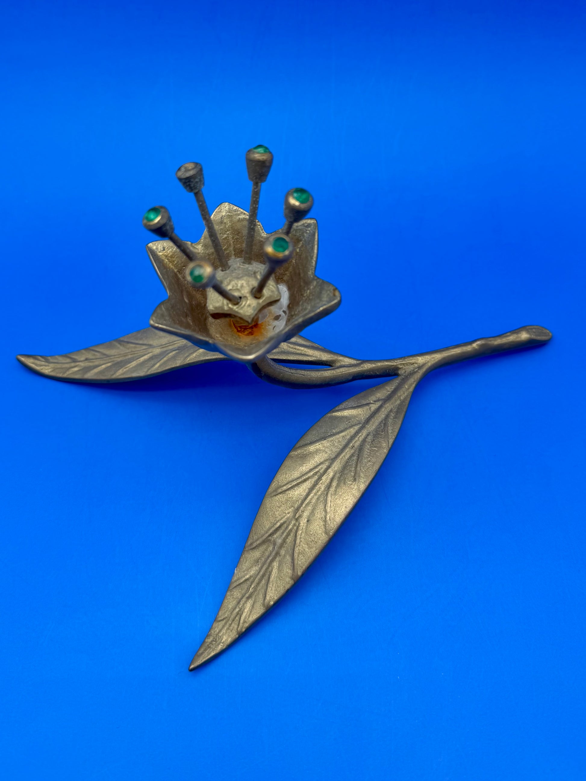 Brass flower-shaped ashtray shown at a closer angle with textured petals visible, blue background