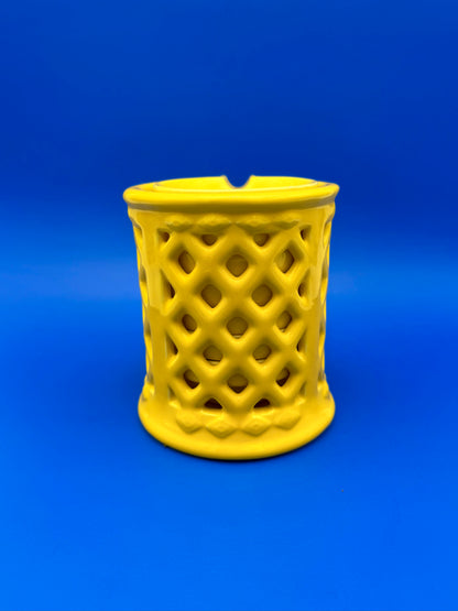 Yellow ceramic lattice ashtray holder shown from a different angle with a diamond cutout pattern, blue background