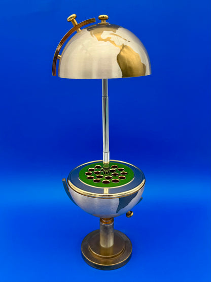 Brass globe cigarette holder open, revealing individual cigarette slots arranged around a green center