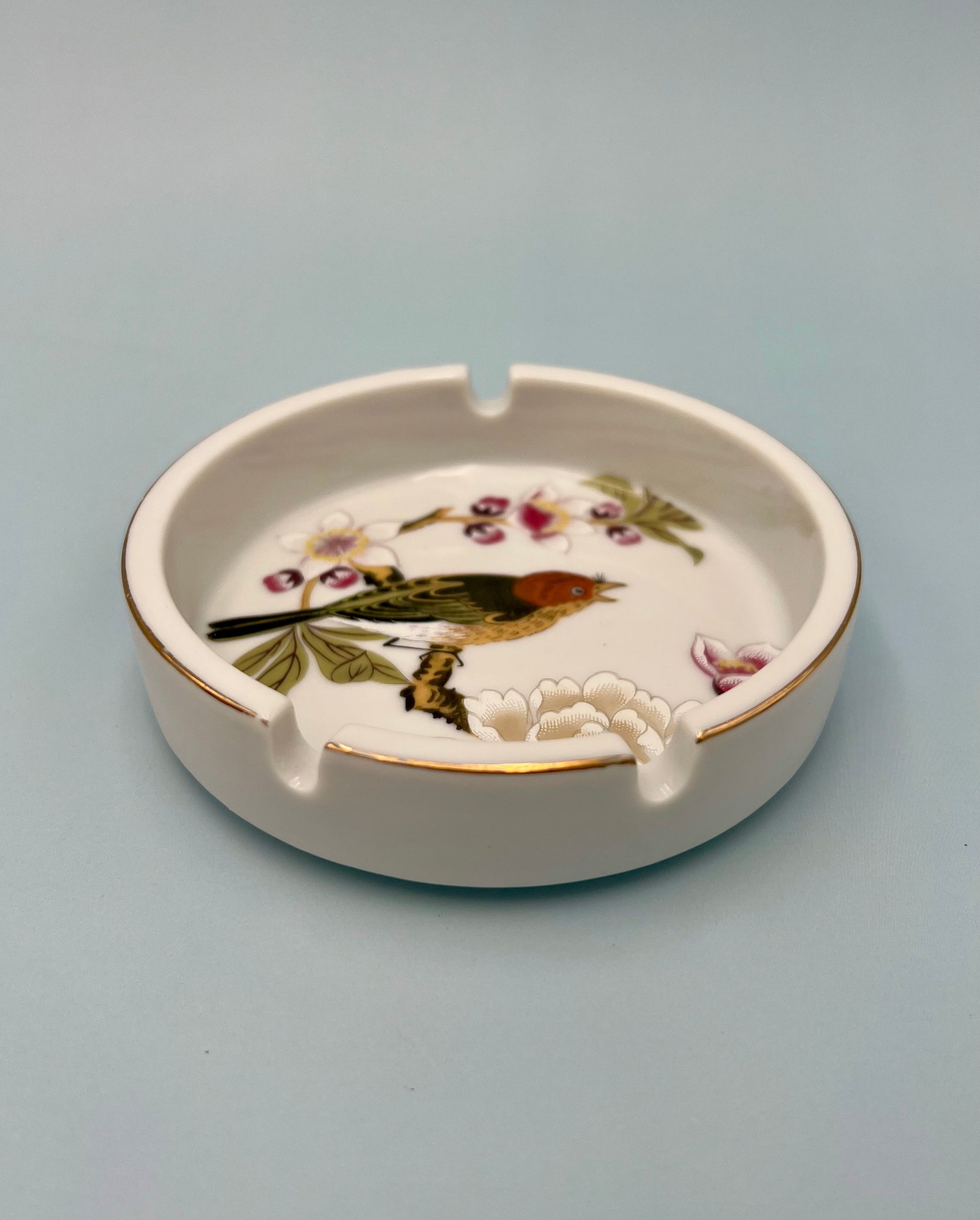 Same round cream ashtray hand-painted with a bird among cherry blossoms, shown without the cigarette pick, closer view, sage green background.