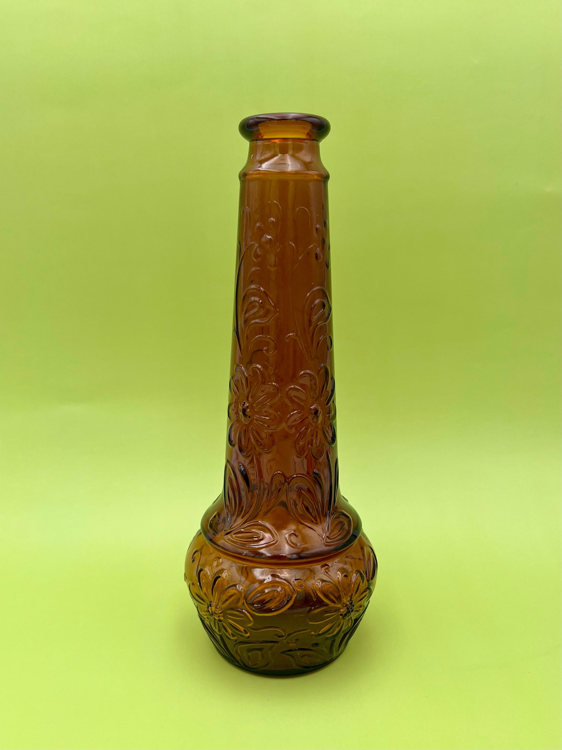 Close-up of the amber daisy-pattern decanter's neck and shoulder detail, chartreuse background