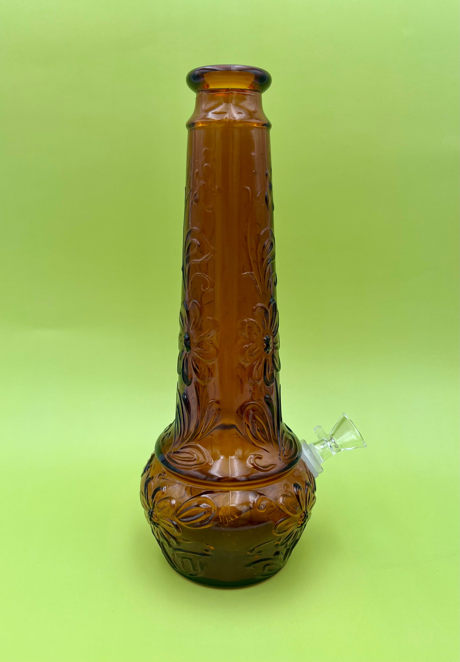 Close-up of the amber daisy-pattern decanter's neck with a small paper tag visible, chartreuse background