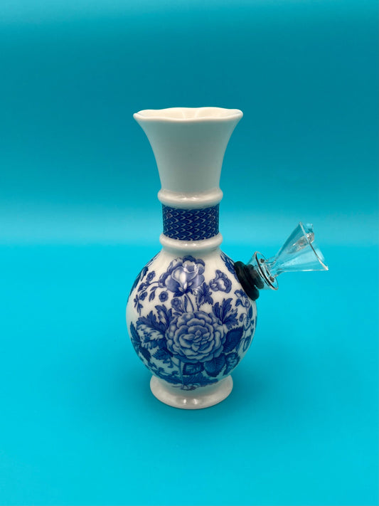 White trumpet-necked porcelain vase water pipe with a blue floral design and a cobalt dotted band, glass mouthpiece attached at the side, teal background