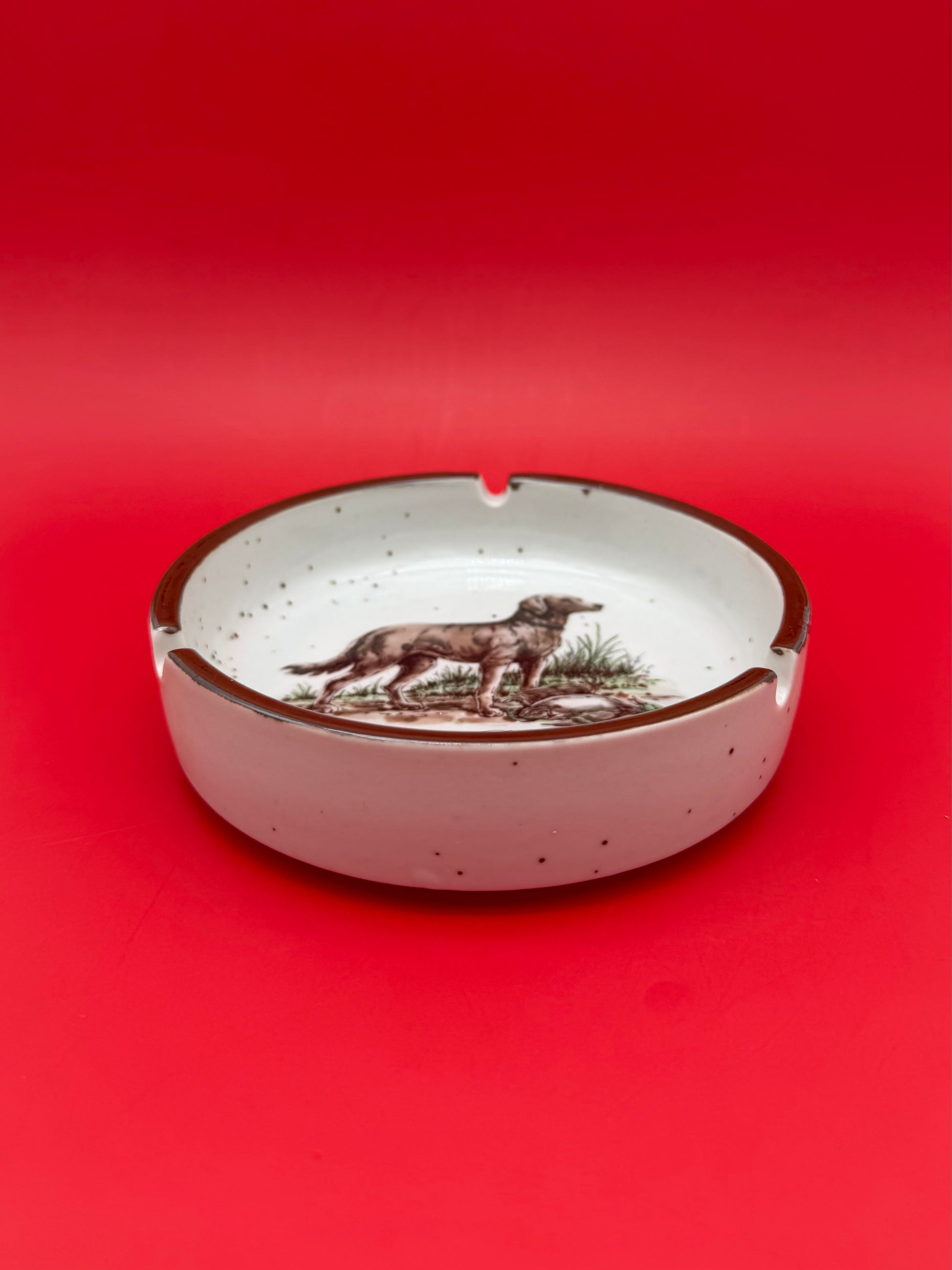 Interior view of the same oval ashtray showing the painted golden retriever illustration, pink-red background.