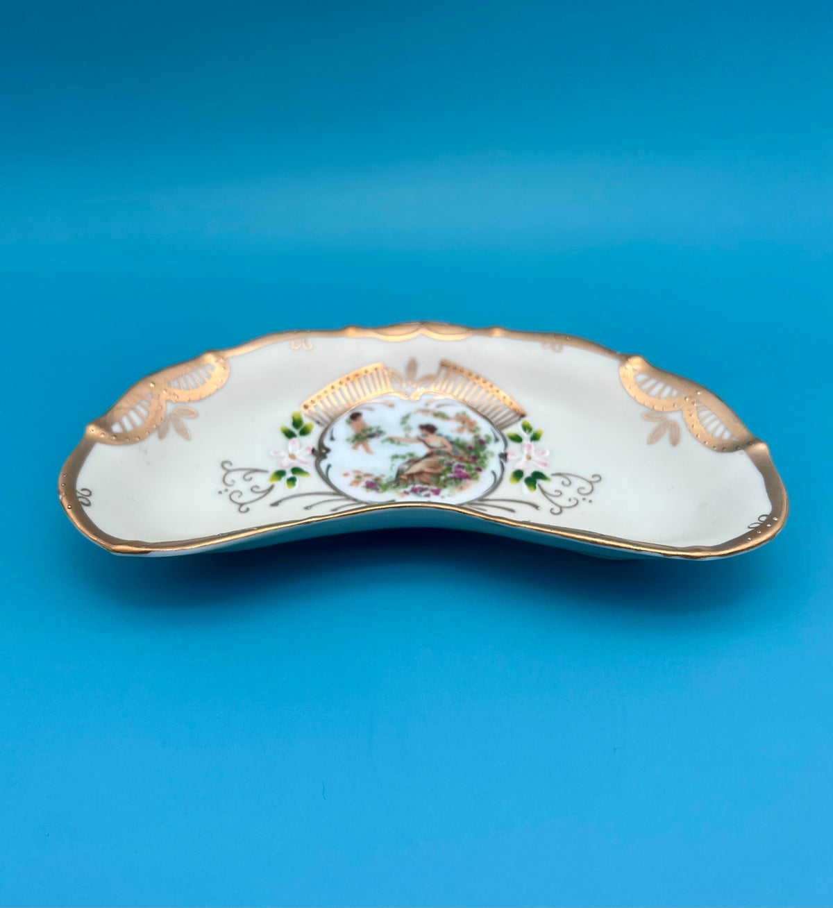 Front view of the crescent-shaped Arabella ashtray with gold scalloped trim, blue background.