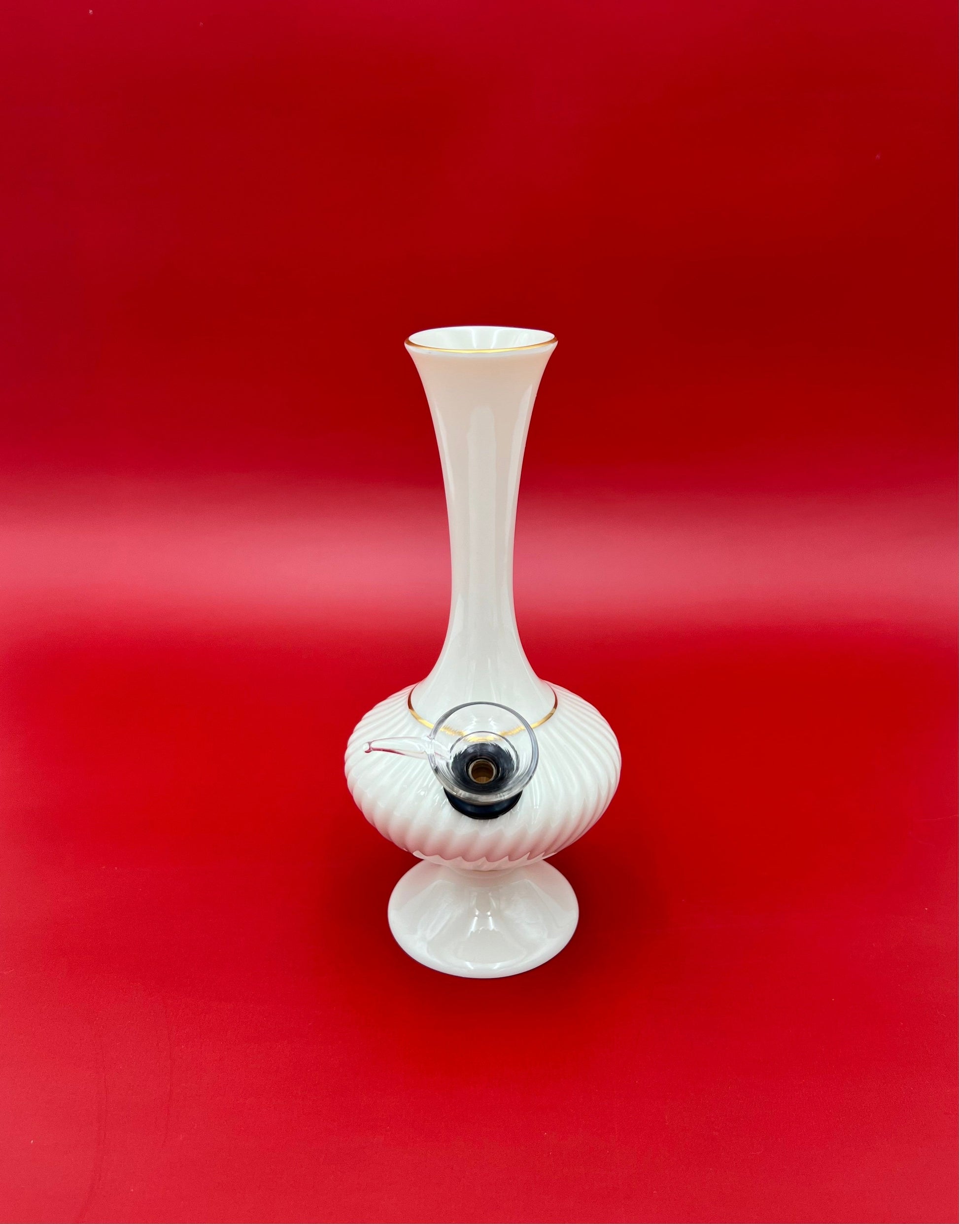 Front view of an ivory ribbed porcelain bud vase water pipe with a fluted trumpet neck, glass bowl piece on the side, deep red background.