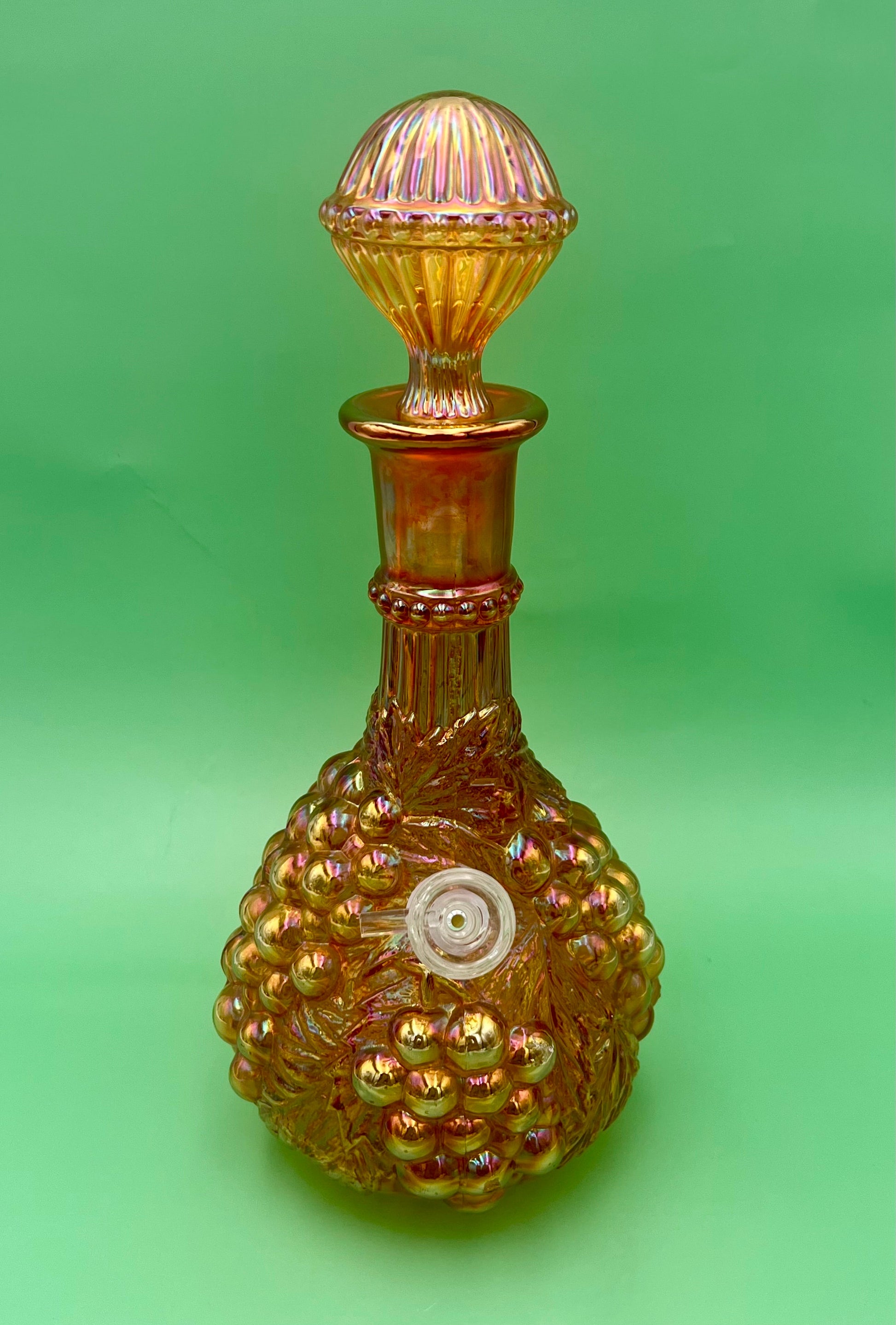 Same marigold iridescent carnival glass decanter with its stopper in place on top, green background