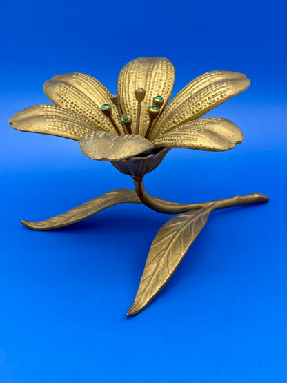 Brass flower-shaped ashtray shown from a different angle highlighting the leaf stem, blue background