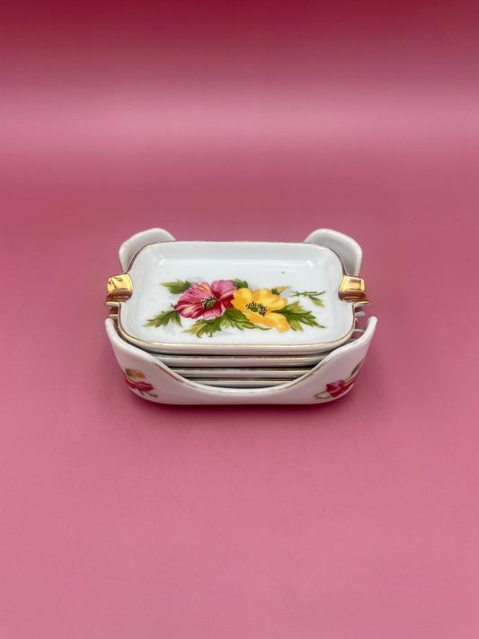 Rectangular porcelain ashtray from the Helen Set with gold handles and an orange and yellow floral pattern, pink background.