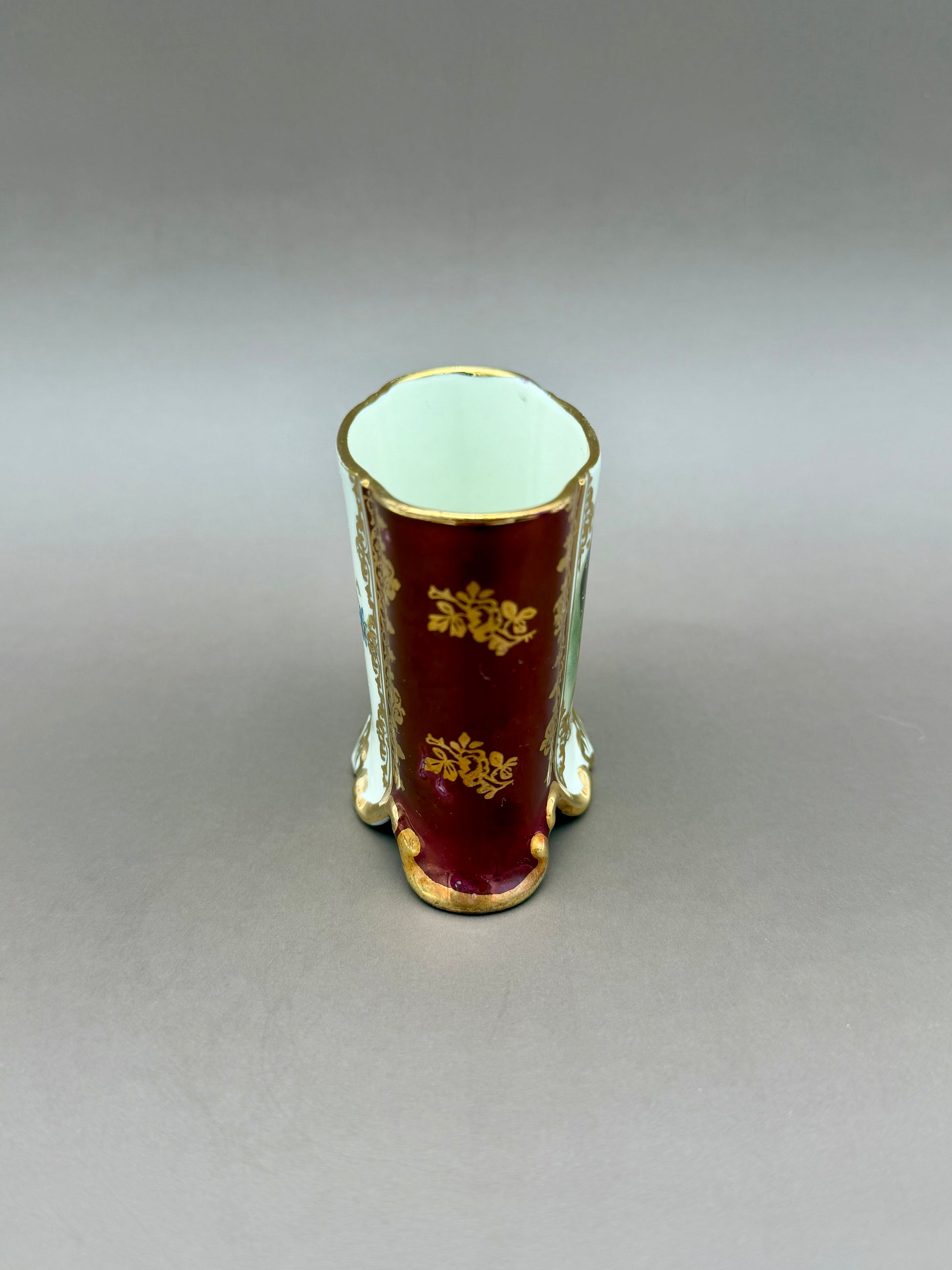 The Henrietta Set cup shown from the opposite side, displaying a plain burgundy panel with gold scrollwork and no portrait, gray background.