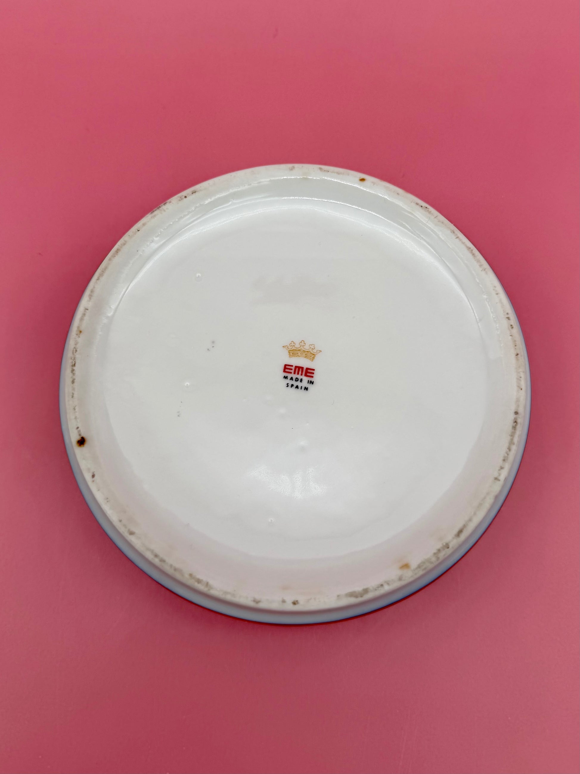 Underside of the same ashtray showing a crown-emblem maker's stamp, pink background.