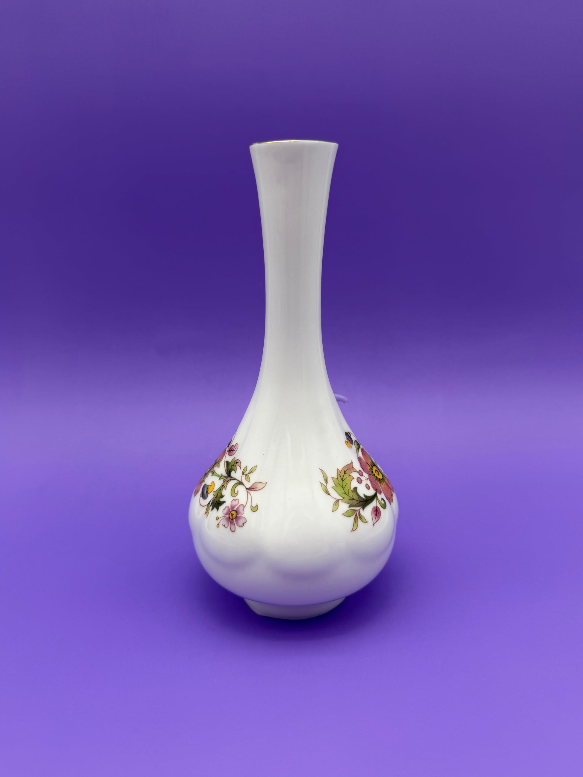 Same white porcelain bud vase water pipe shown without the bowl piece attached, front view of the floral band, purple background.