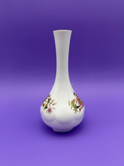 Same white porcelain bud vase water pipe shown without the bowl piece attached, front view of the floral band, purple background.