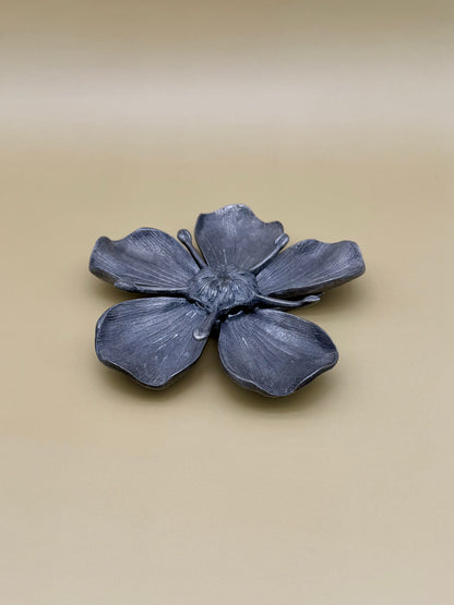 Silver marigold flower-shaped dish viewed from an angled side view, tan background.