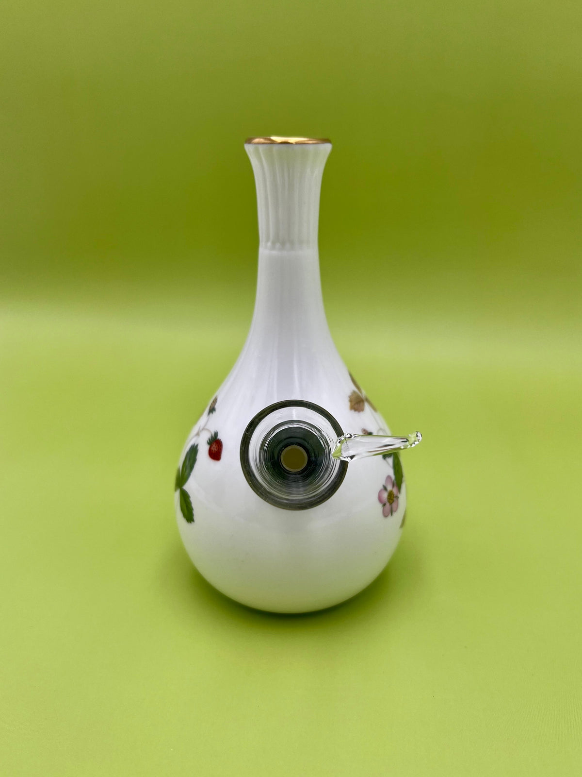 Same white strawberry-pattern bud vase with the glass mouthpiece and metal ring attached lower on the body, olive-green background
