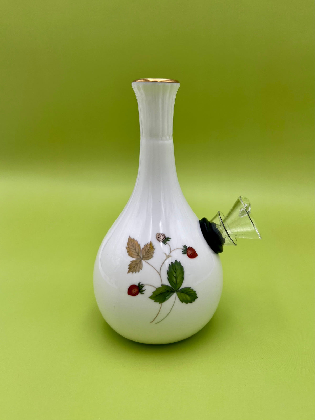 Same white strawberry-pattern bud vase with a glass mouthpiece attached at the side, showing more of the floral design, olive-green background