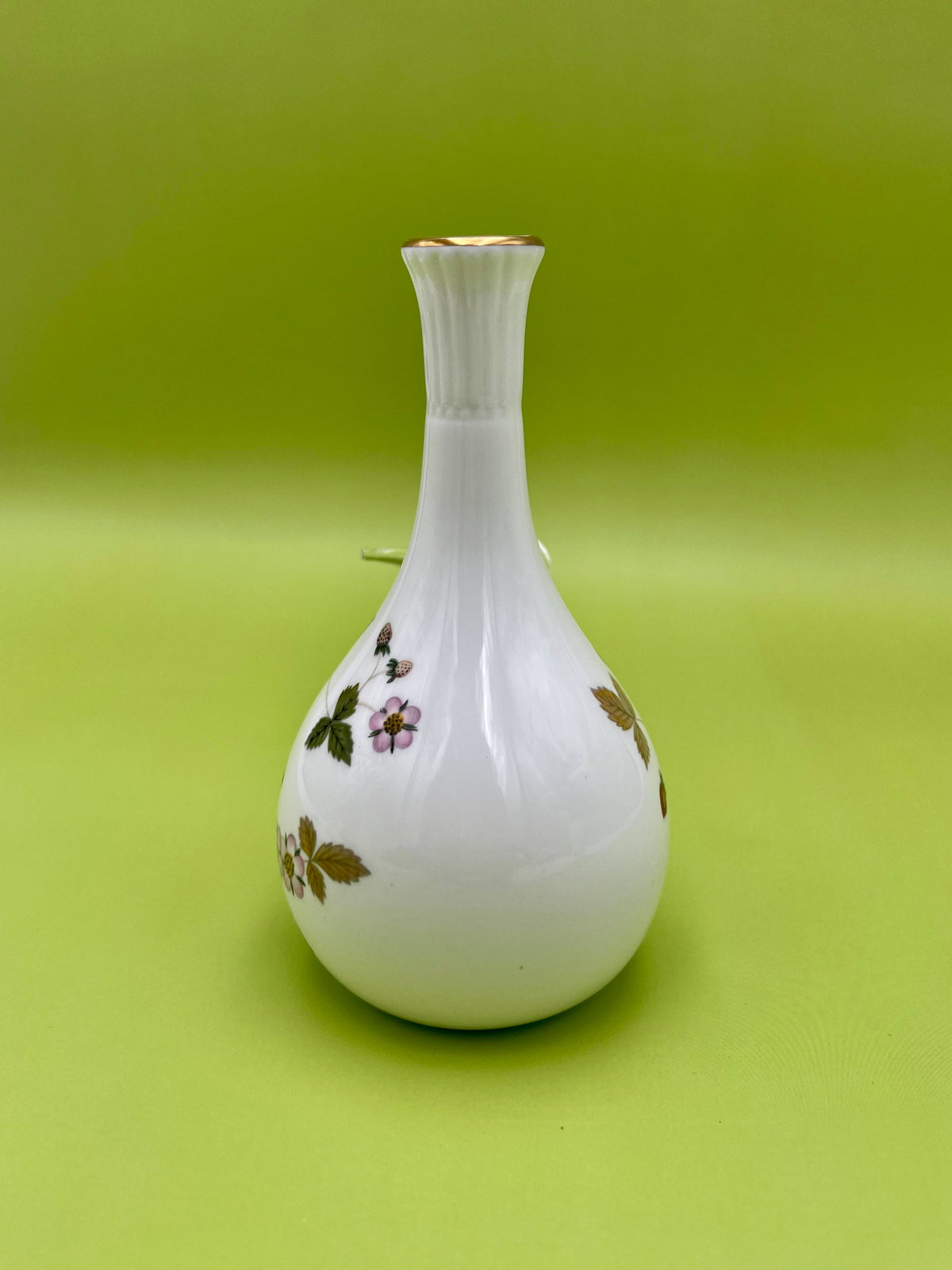 Same white strawberry-pattern bud vase in a plain view with no attachment visible, olive-green background