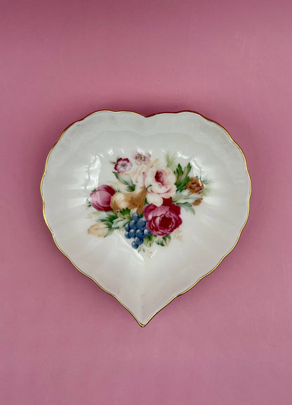 Heart-shaped white porcelain dish with a hand-painted floral bouquet and gold trim, mauve background.
