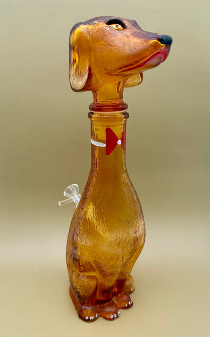 Amber glass decanter water pipe shaped like a dachshund dog, tan background.