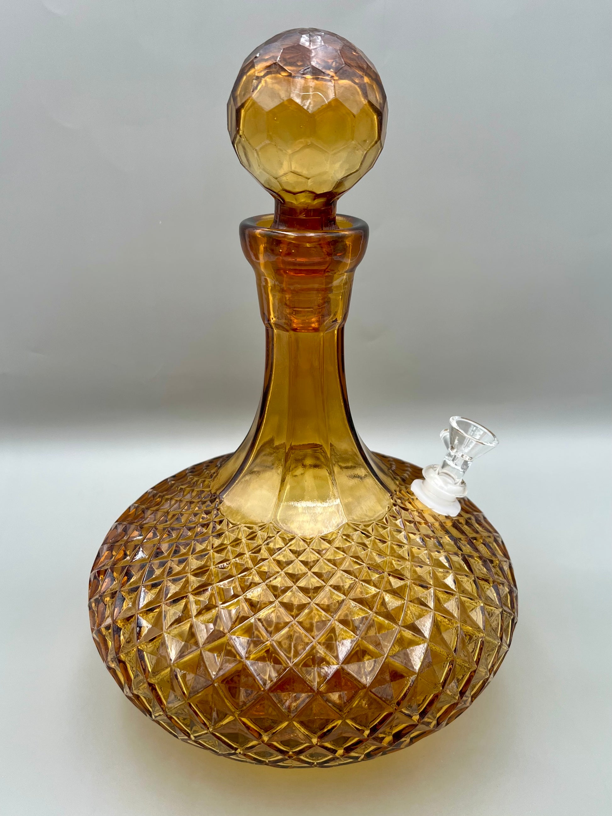 Same amber cut-glass decanter with its stopper in place, shown without the bowl piece, gray background.